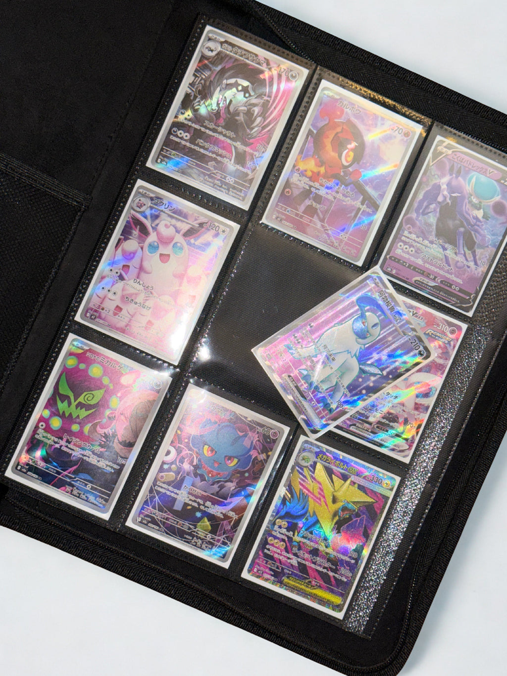 Collection of colorful trading cards in a black holder on a white background showing the side loading abilities of the Trova Binder Collection